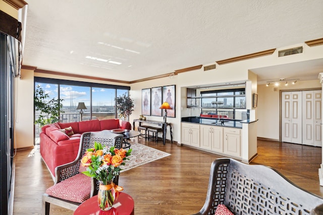 living room with ornamental molding, a textured ceiling, and wood finished floors