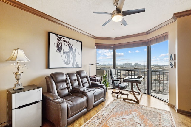 living room with ornamental molding, light wood finished floors, a ceiling fan, and a textured ceiling