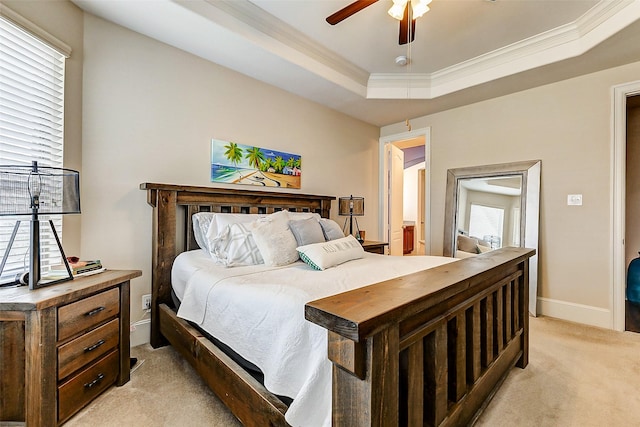 bedroom featuring light carpet, a tray ceiling, ornamental molding, and ceiling fan