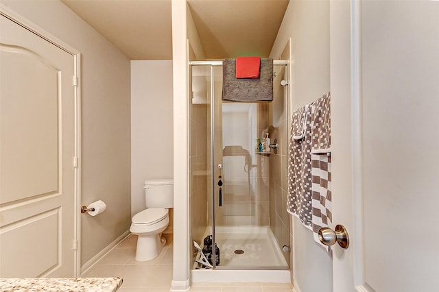 bathroom with a shower stall, toilet, and tile patterned floors