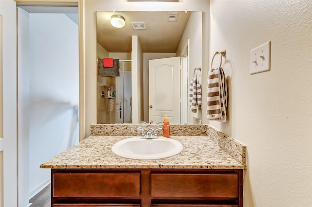 bathroom featuring wood finished floors, visible vents, vanity, and a stall shower