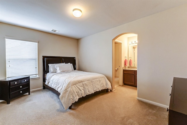 bedroom with baseboards, arched walkways, visible vents, and light carpet