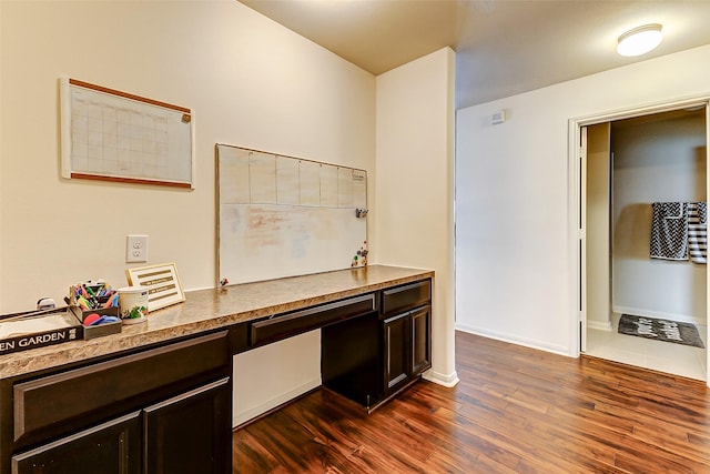 unfurnished office with baseboards, dark wood-style flooring, and built in desk