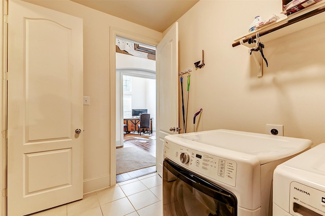 clothes washing area with baseboards, washing machine and clothes dryer, laundry area, and light tile patterned floors