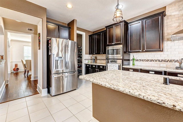 kitchen featuring light stone counters, visible vents, decorative backsplash, and stainless steel appliances
