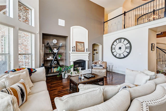 living area featuring wood finished floors, a towering ceiling, and a fireplace with raised hearth