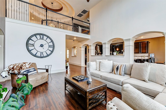 living area with arched walkways, a towering ceiling, and ornate columns