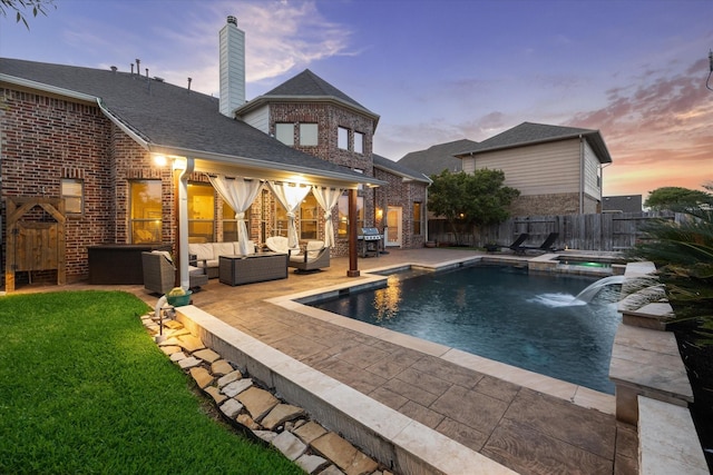 pool at dusk with a lawn, outdoor lounge area, grilling area, a fenced backyard, and a patio