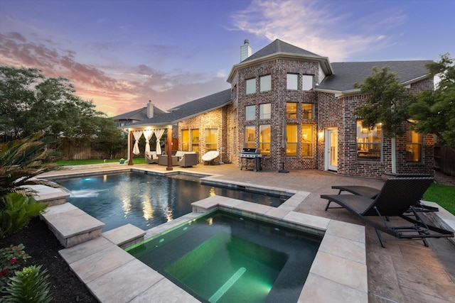 rear view of property featuring a chimney, brick siding, a patio area, and an outdoor hangout area