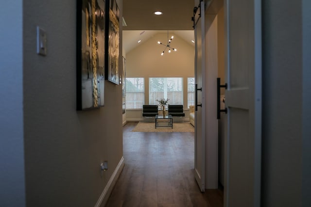 hallway with a barn door, baseboards, recessed lighting, lofted ceiling, and wood finished floors