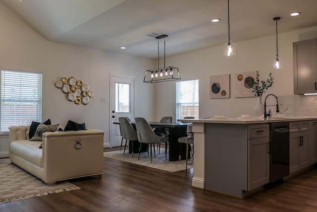 kitchen featuring dark wood finished floors, tasteful backsplash, a sink, and dishwashing machine