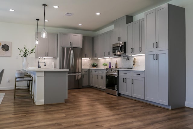kitchen featuring a peninsula, visible vents, gray cabinetry, appliances with stainless steel finishes, and a breakfast bar area
