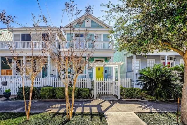 view of front of property featuring a balcony, a fenced front yard, and a gate