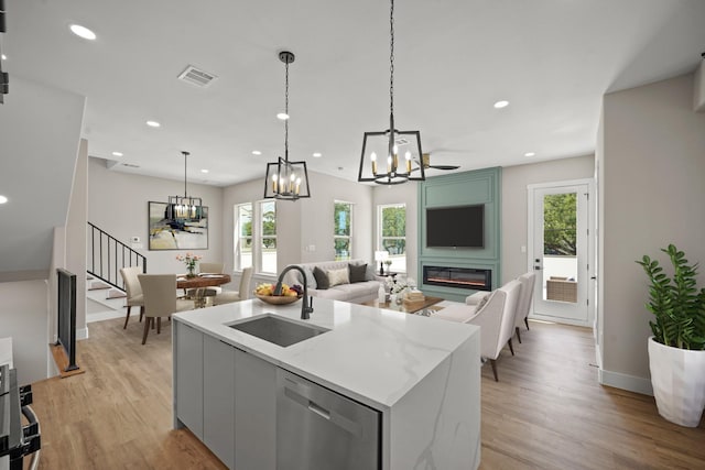 kitchen featuring a sink, a chandelier, dishwasher, light wood-style flooring, and visible vents
