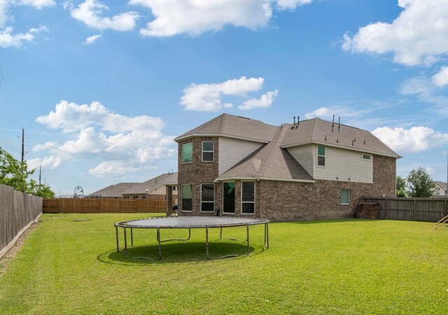 3203 Jeanette Cir, Mont Belvieu, TX 77523 - rear view of property featuring a trampoline and brick siding