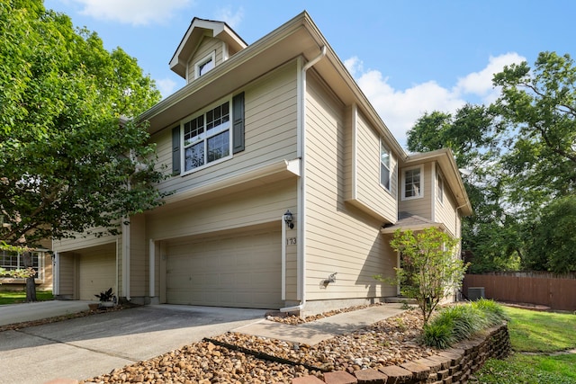 view of side of property with fence, driveway, and a garage
