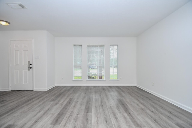 unfurnished living room featuring wood finished floors, visible vents, and baseboards