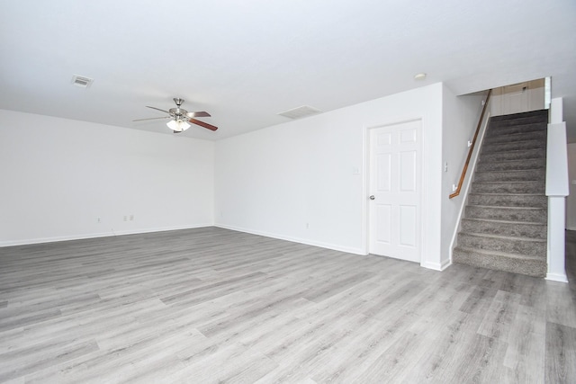unfurnished room featuring a ceiling fan, visible vents, stairs, and light wood-style flooring