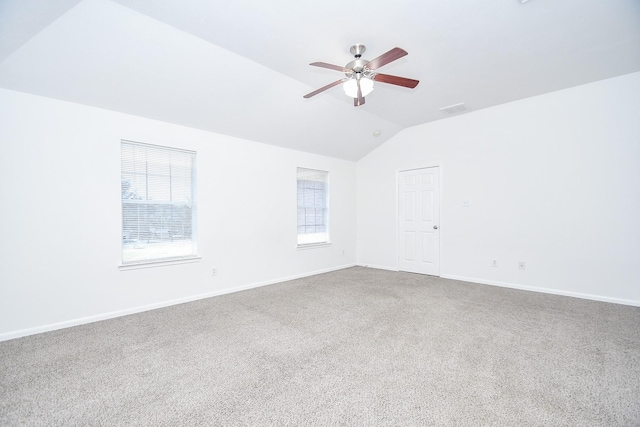 spare room with lofted ceiling, carpet floors, a ceiling fan, and baseboards