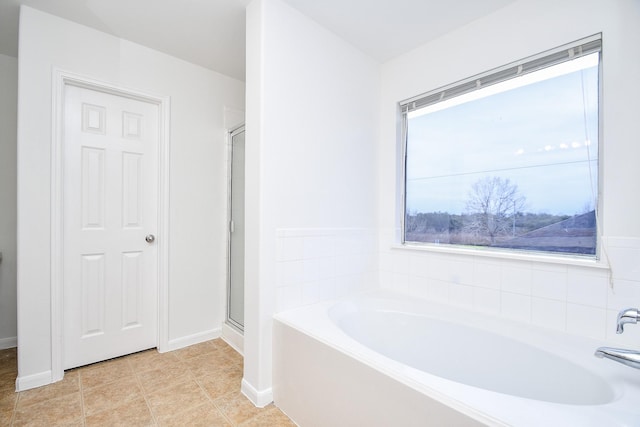 full bathroom featuring a garden tub, baseboards, and a shower stall