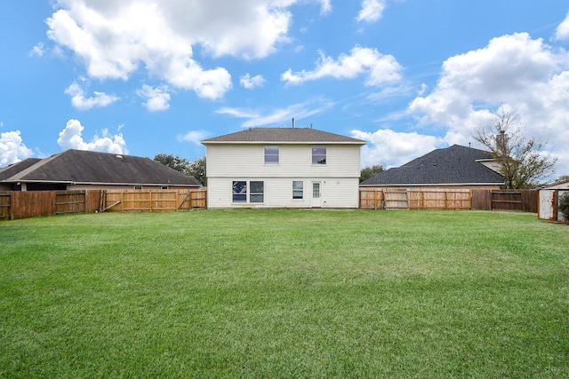 rear view of house featuring a lawn and a fenced backyard