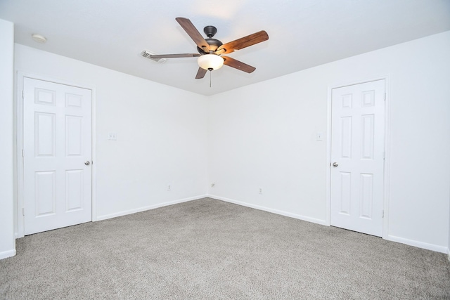 carpeted empty room featuring baseboards, a ceiling fan, and visible vents