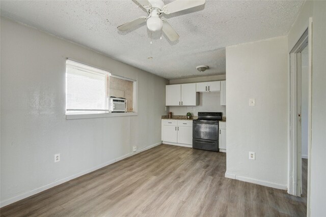 5409 Suez St Unit 4, Houston, TX 77020 - kitchen featuring white cabinets, wood finished floors, a textured ceiling, and black electric range