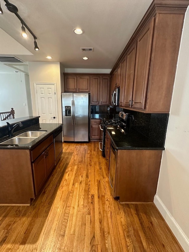 kitchen with a sink, stainless steel appliances, light wood finished floors, baseboards, and visible vents