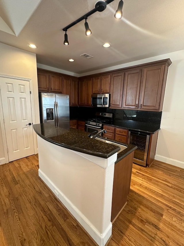 kitchen featuring light wood-style flooring, baseboards, beverage cooler, and appliances with stainless steel finishes