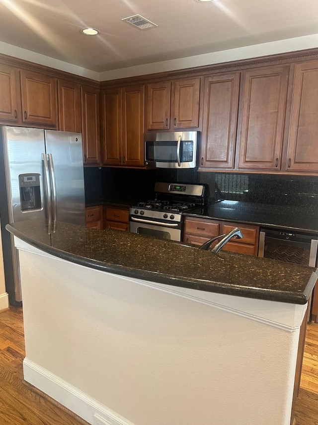 kitchen featuring dark stone countertops, stainless steel appliances, visible vents, and a sink