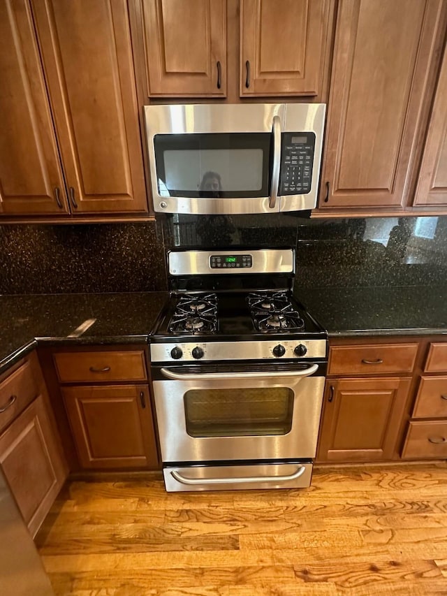kitchen with backsplash, light wood-style floors, brown cabinets, and stainless steel appliances