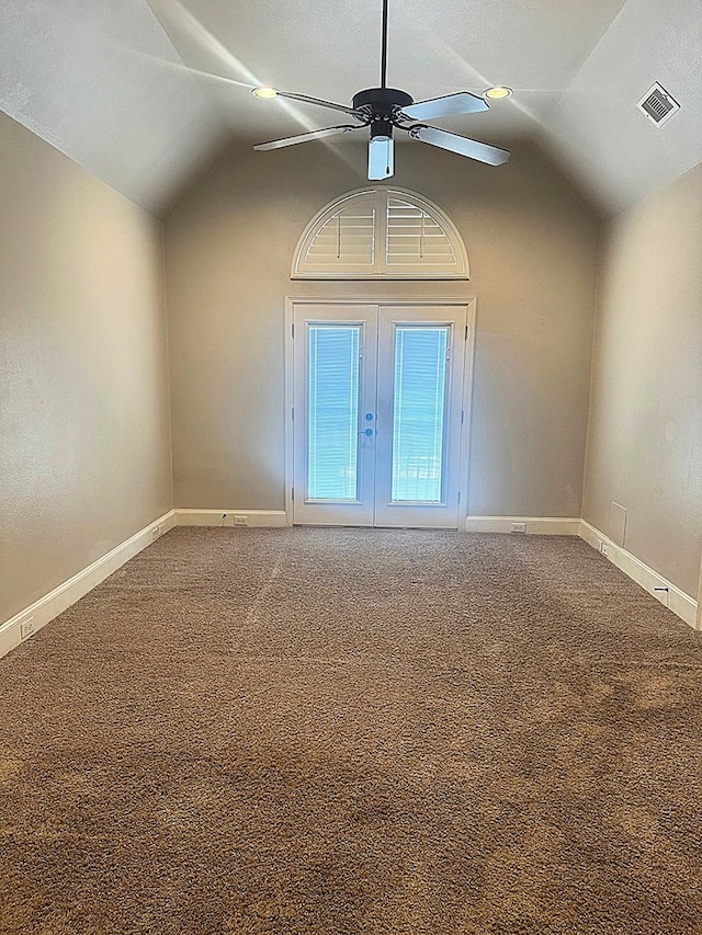 carpeted empty room featuring lofted ceiling, a ceiling fan, visible vents, and baseboards