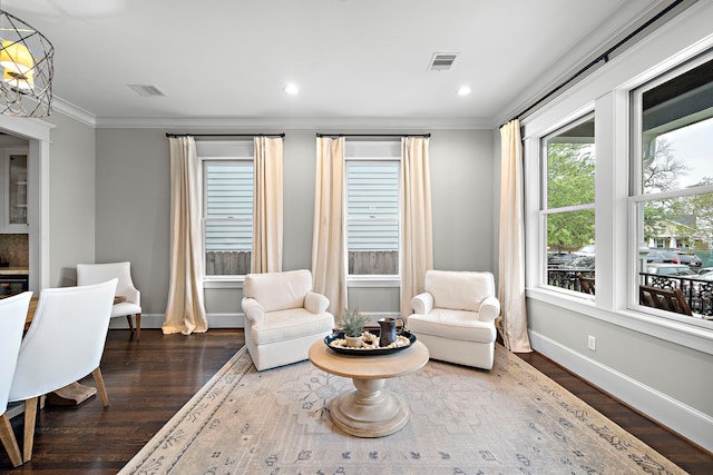 sitting room with wood finished floors, visible vents, crown molding, and baseboards
