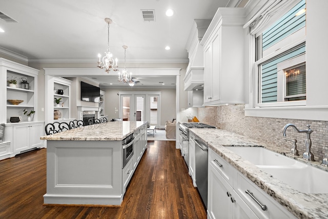 kitchen featuring crown molding, a sink, visible vents, and a kitchen island