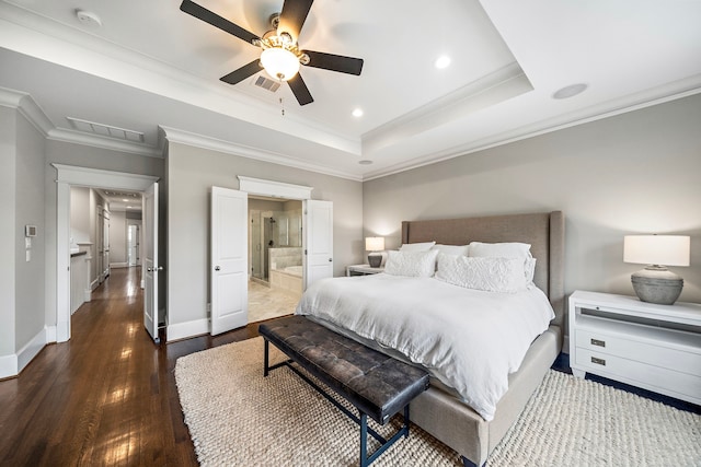 bedroom with crown molding, wood finished floors, a tray ceiling, and visible vents