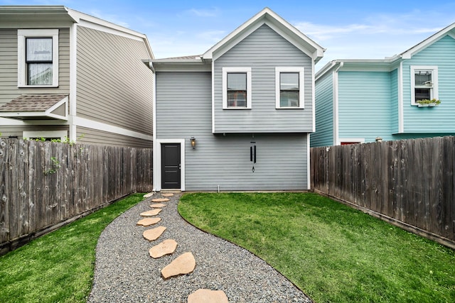 rear view of house featuring a yard and a fenced backyard