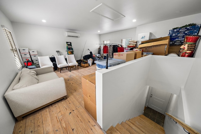 interior space featuring attic access, a wall mounted air conditioner, hardwood / wood-style flooring, and recessed lighting