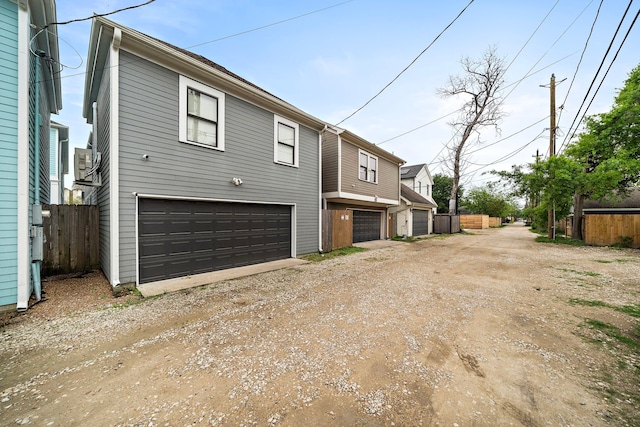 exterior space featuring an attached garage, driveway, and fence