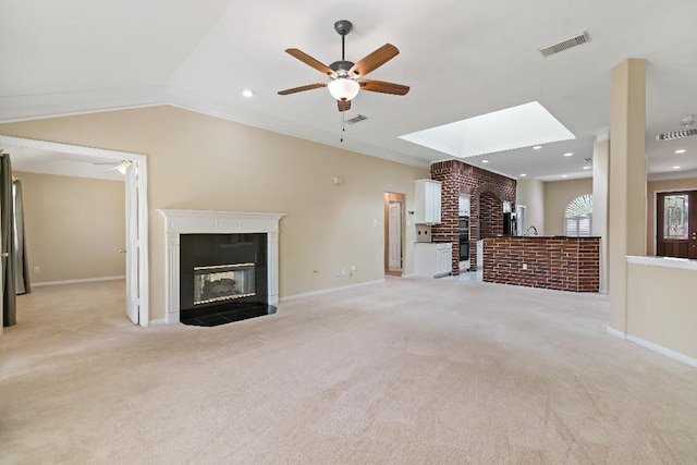 2538 Silent Shore Ct, Richmond, TX 77406 - unfurnished living room featuring a glass covered fireplace, light carpet, a ceiling fan, a skylight, and recessed lighting