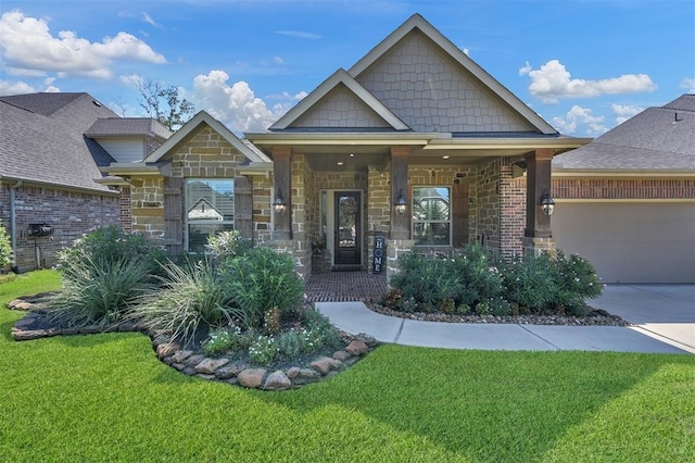 craftsman-style home featuring an attached garage, a front lawn, stone siding, covered porch, and driveway