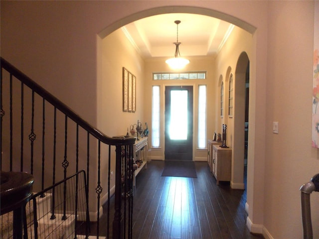 23423 Tavola Rosa Dr, New Caney, TX 77357 - foyer entrance featuring a tray ceiling, baseboards, dark wood-style flooring, crown molding, and arched walkways