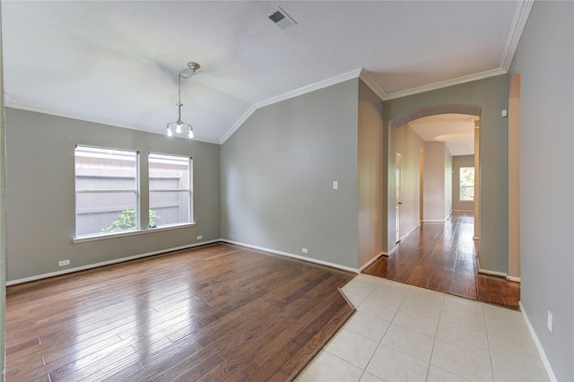 empty room featuring vaulted ceiling, arched walkways, crown molding, and wood finished floors