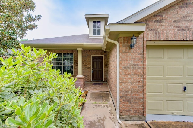 entrance to property with brick siding and a garage