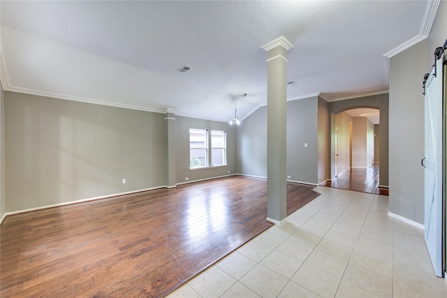 unfurnished room featuring visible vents, arched walkways, light wood-type flooring, crown molding, and decorative columns