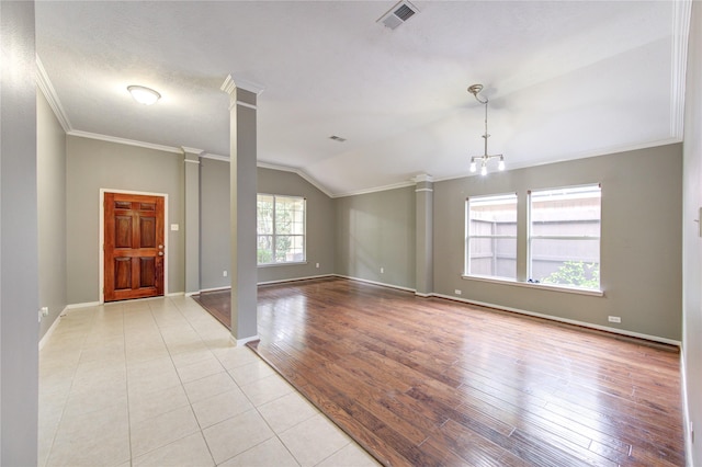 empty room featuring crown molding, baseboards, lofted ceiling, visible vents, and ornate columns