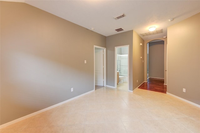 spare room with baseboards, visible vents, arched walkways, and light tile patterned floors