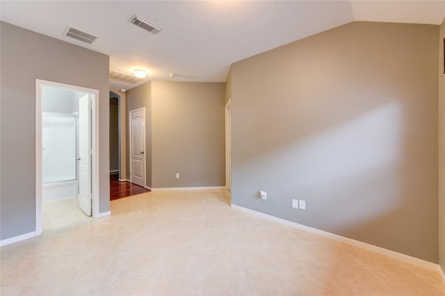 empty room featuring lofted ceiling, baseboards, visible vents, and light tile patterned floors