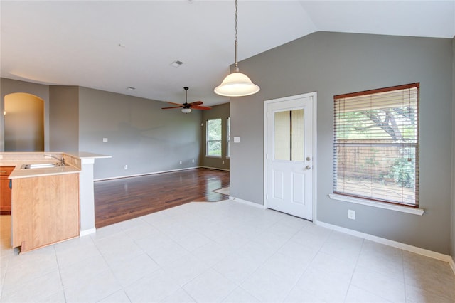 interior space featuring vaulted ceiling, baseboards, ceiling fan, and a sink
