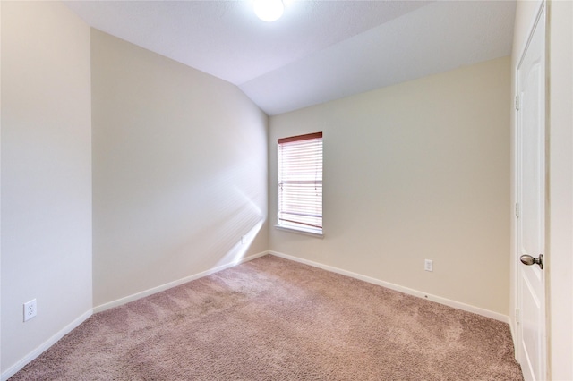 spare room with baseboards, lofted ceiling, and carpet
