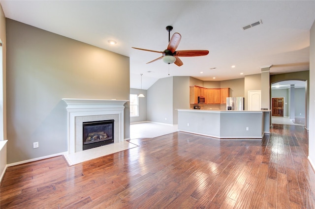 unfurnished living room with a fireplace with flush hearth, dark wood finished floors, vaulted ceiling, visible vents, and a ceiling fan